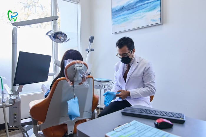 A dentist talking to a patient sitting on a dentist chair