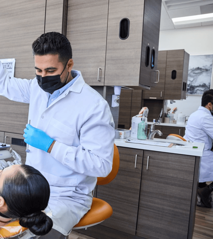 A dentist wearing a white robe and a face mask
