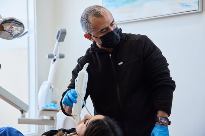 A dentist wearing a black robe talking to a patient