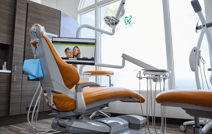 A dental chair in front of a monitor