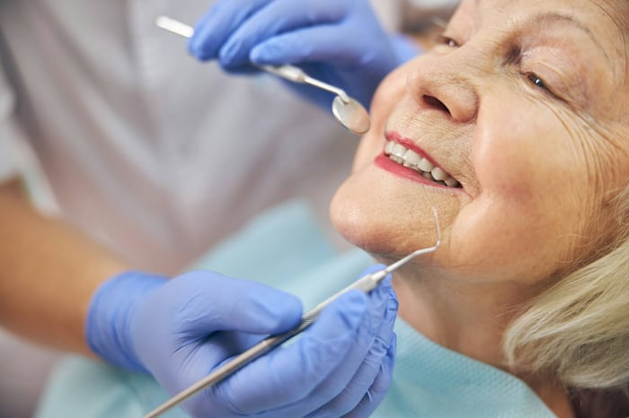 An old woman being checked by a dentist