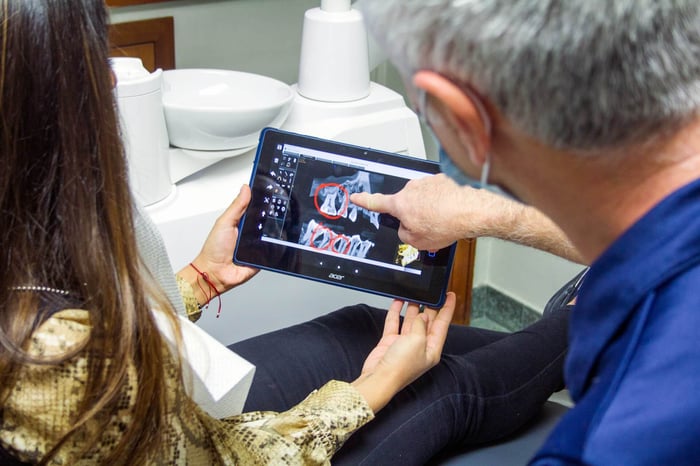 Two person talking to each other over a tablet showing a teeth structure