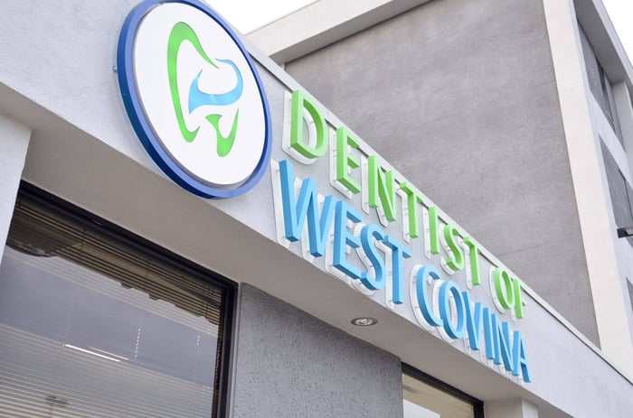 Exterior sign reading Dentist of West Covina displayed on the front of a modern dental office building.
