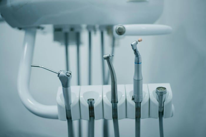Close-up of dental handpieces and tools attached to a modern dentist chair unit.
