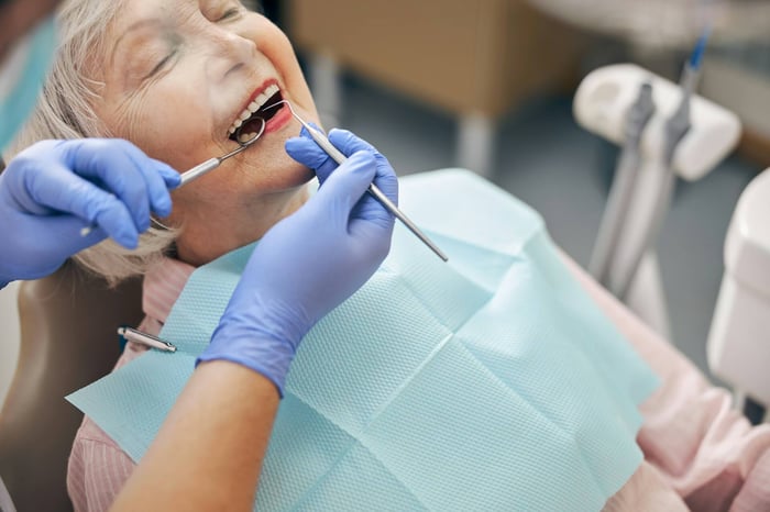 An old woman being checked by a dentist