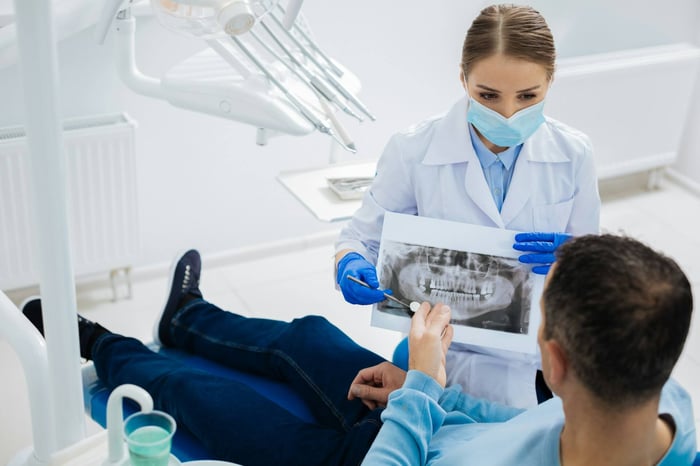 A dentist talking to a patient sitting on a dentist chair