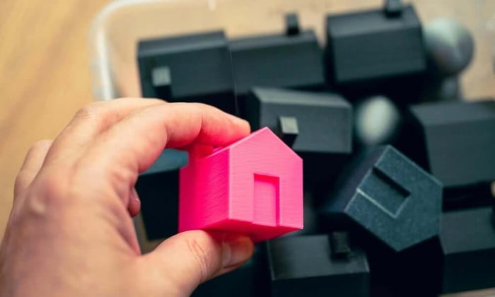 Property manager holding miniature house model representing vacation home protected by cellular temperature monitor