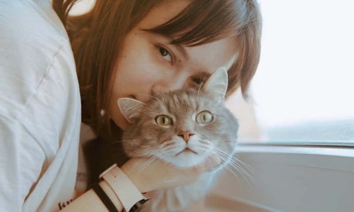 Woman holding a cat by a window inside a prepared pet safe room designed to keep pets comfortable while home alone