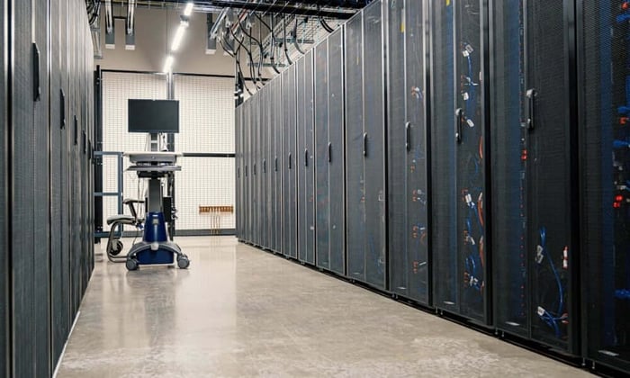 server room with rows of black equipment racks and visible cable management in a climate-controlled data center