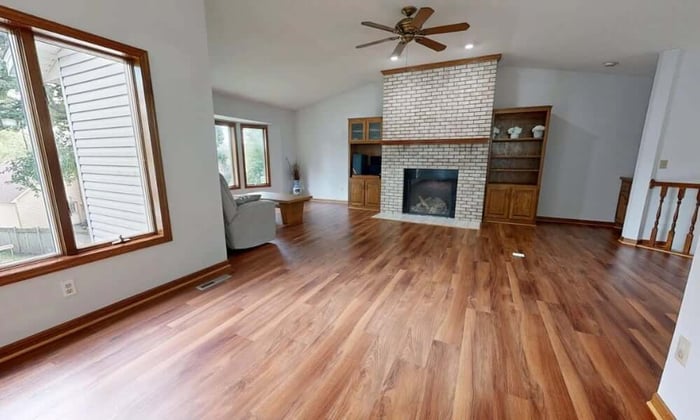 Empty living room in vacant property showing hardwood floors and fireplace where temperature monitoring prevents damage