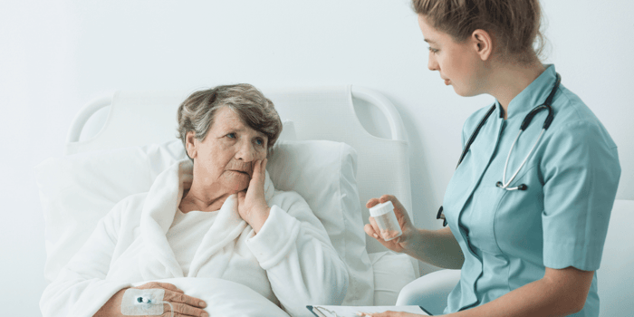 Registered nurse reviewing a postoperative pain assessment with an older adult patient while preventing chronic postsurgical pain risk.