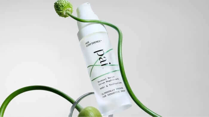 Pai Skincare Age Confidence serum bottle with NAD+ and TriPeptide formula surrounded by curved green plant stems