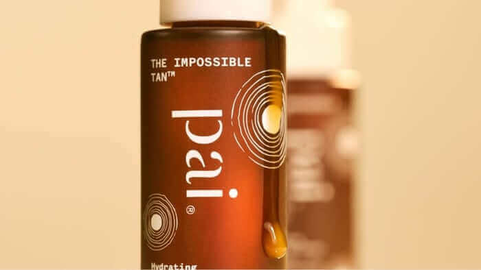 The Impossible Tan self tan drops bottle in warm amber gradient packaging with golden droplet design