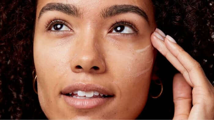 Close-up of woman with glowing skin applying echium skincare product, showcasing smooth complexion and anti-aging benefits
