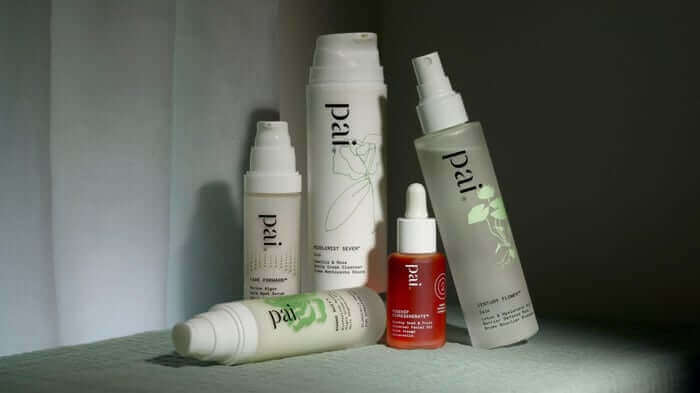 Pai Skincare evening routine products on mint green surface including cleansers, rosehip oil serum and moisturizers for nighttime skincare