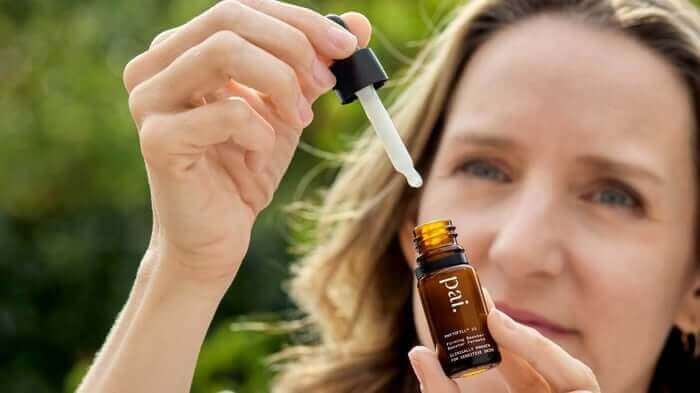 Woman applying Pai Rosehip BioRegenerate Oil with dropper pipette for natural anti-aging skincare