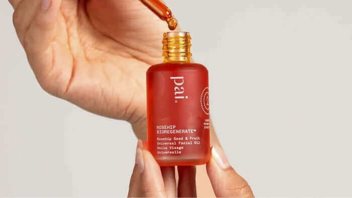 Hand holding Pai Rosehip BioRegenerate Oil bottle with dropper, showing the amber-colored facial oil for anti-aging skincare