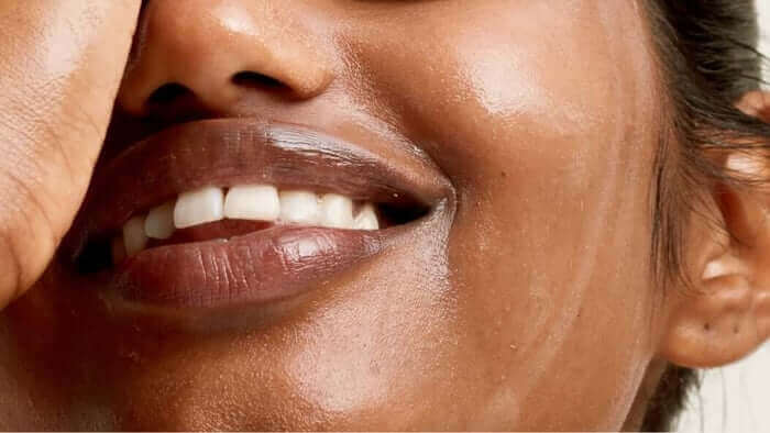 Close-up of woman's genuine smile showing natural skin texture with visible pores and authentic glow