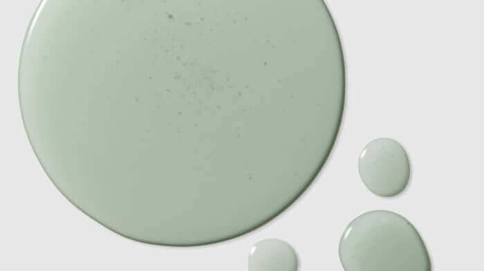 Close-up of sage green skincare product texture with smooth droplets, showing the creamy consistency of PHAZE moisturizer