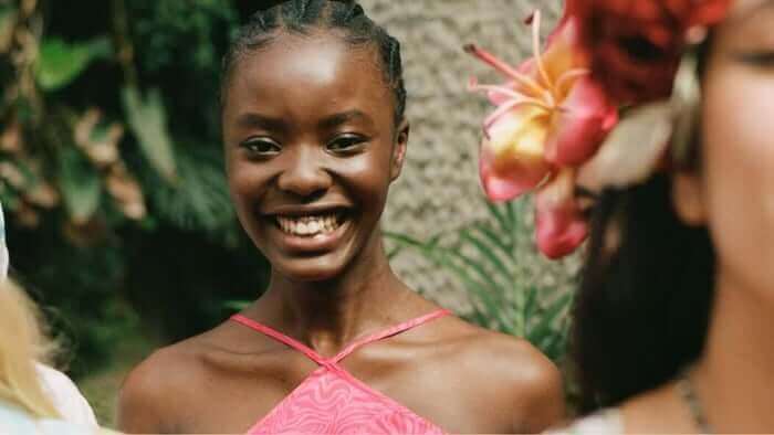 Smiling woman with natural glowing skin in tropical garden setting with vibrant flowers