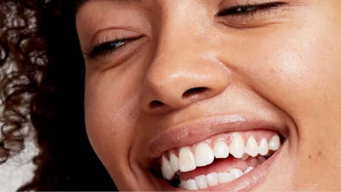 Close-up of woman with glowing, healthy skin smiling joyfully, showcasing radiant complexion and natural beauty
