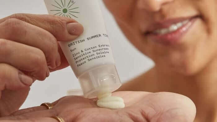 Hand dispensing British Summer Time SPF cream onto palm, showing the white sunscreen texture for sensitive skin protection