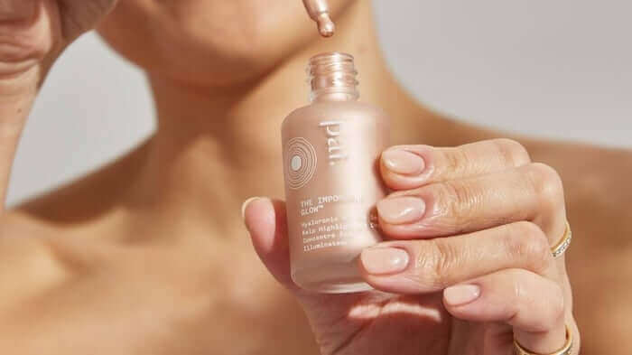 Woman holding Light Work rosehip cleansing oil in frosted glass bottle with dropper, perfect for adding glow to skincare routine