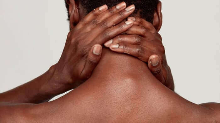 Hands gently massaging the back of neck and shoulders, demonstrating gentle skincare routine for sensitive skin