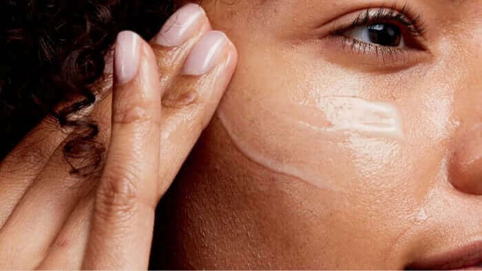 Woman applying moisturiser to glowing skin with gentle upward hand movements