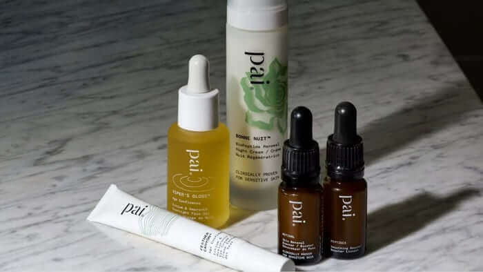 Collection of Pai Skincare products for menopausal skin care including rosehip oil, serum, and moisturiser arranged on marble surface