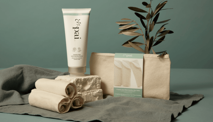 Pai Skincare cleanser tube with rolled muslin cloths and natural product packaging on sage green background