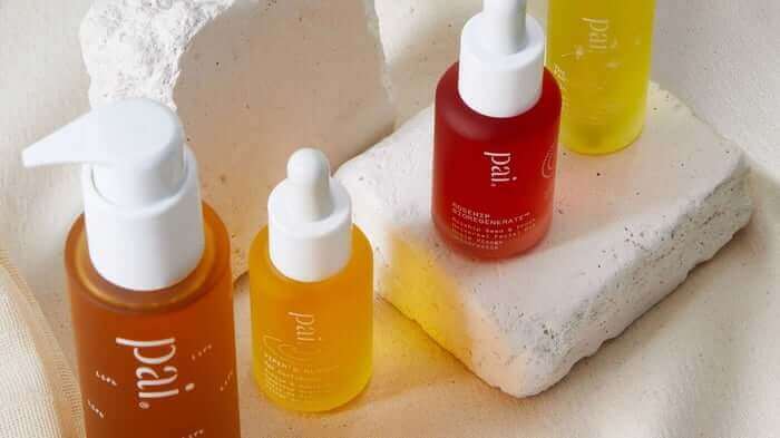 Four Pai Skincare award-winning face oils in amber, yellow and red bottles with dropper caps arranged on white stone blocks
