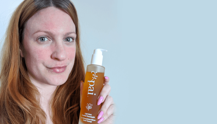 Woman with rosacea holding Pai Rosehip BioRegenerate Oil, showing visible facial redness