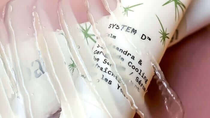 Creamy white eye serum being dispensed from clear pump bottle with botanical leaf pattern packaging