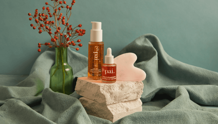 Pai Light Work Rosehip Cleansing Oil and Rosehip BioRegenerate Oil with rose quartz gua sha on natural stone platform