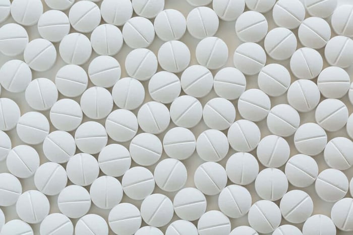 White pharmaceutical tablets scattered on neutral background representing hormonal contraceptive pills