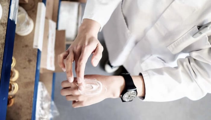 Hands applying white skincare cream showing patch testing technique for sensitive skin safety