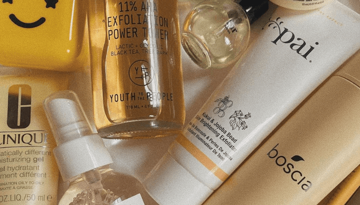Pai Kukui & Jojoba Bead Skin Brightening Exfoliator tube among skincare products in warm golden light, gentle exfoliator for sensitive skin