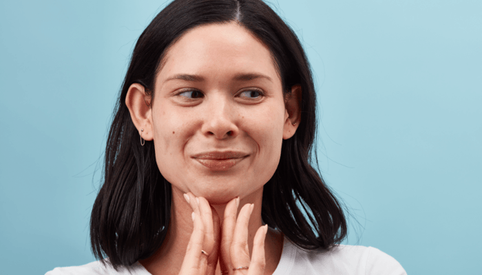 Woman with clear skin gently touching neck area, demonstrating hydrated complexion after using serum