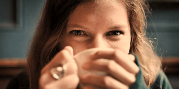 Woman holding coffee mug with visible under-eye area showing natural skin texture