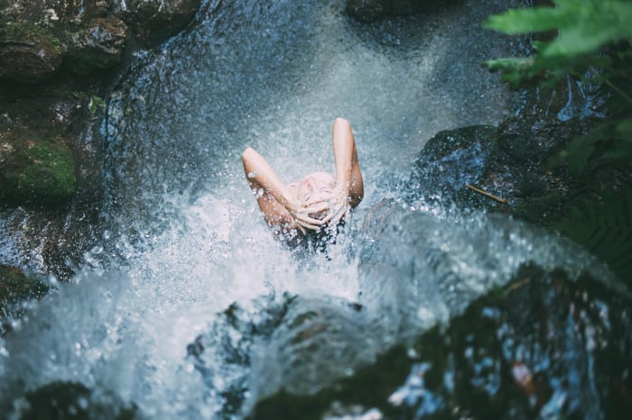 Hands cupping pure natural water from a forest stream, symbolizing gentle cleansing