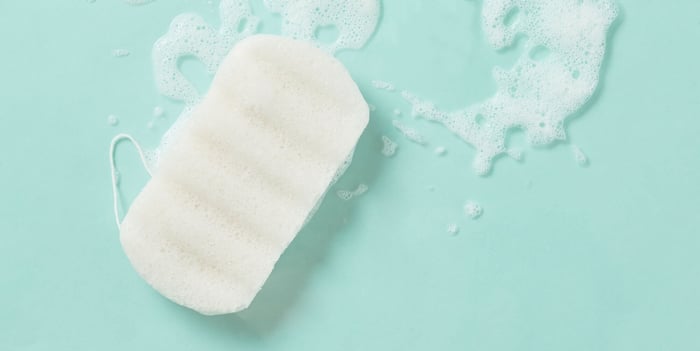 White konjac sponge floating in mint green water with gentle bubbles for natural facial cleansing
