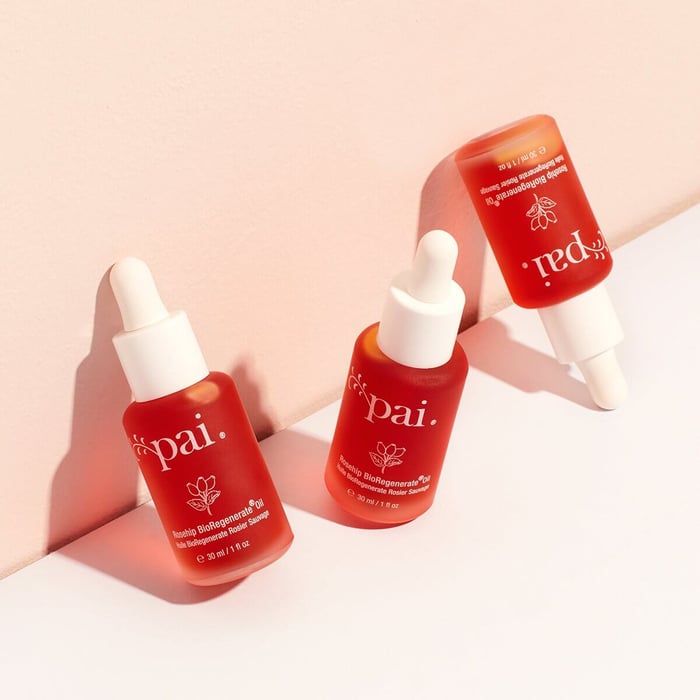 Three bottles of Pai Rosehip BioRegenerate Oil with white droppers arranged on blush pink background with soft shadows