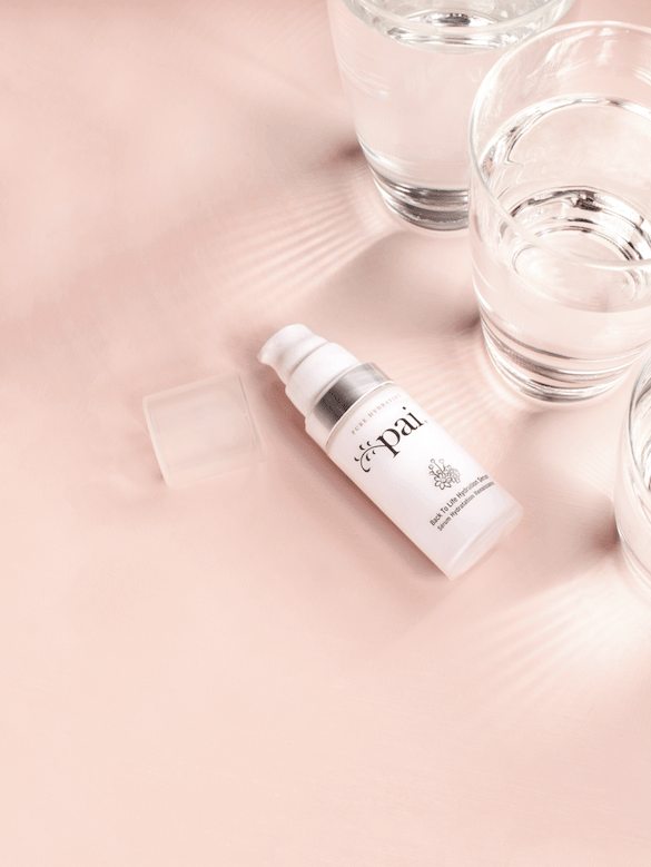 Back to Life Hydration Serum bottle with clear glasses of water on soft pink surface