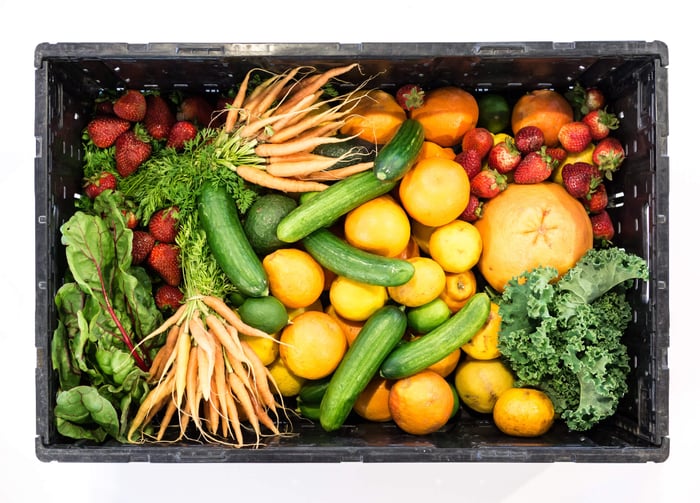 Fresh colorful vegetables and fruits in wooden crate including leafy greens, strawberries, oranges and cucumbers rich in natural quercetin