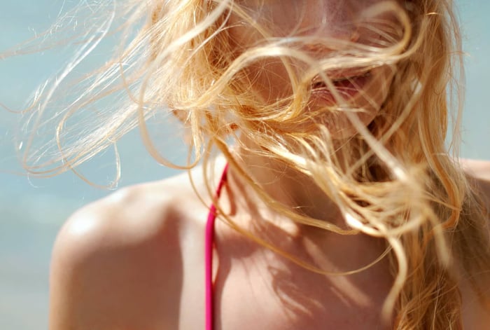 Woman with flowing blonde hair in sunlight, showing healthy scalp and hair movement