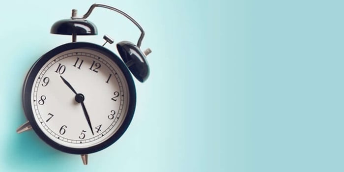 Vintage alarm clock on soft blue background representing slow beauty and taking time for mindful skincare routines