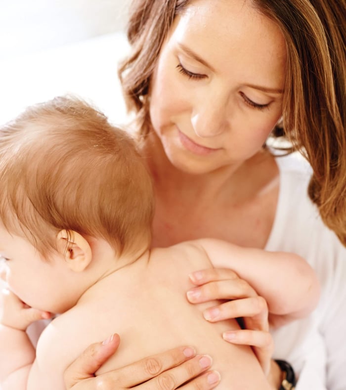 Mother gently cradling baby with smooth healthy scalp after cradle cap treatment