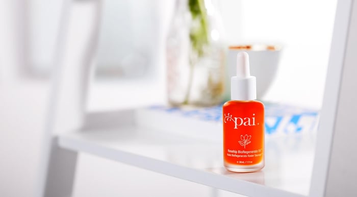 Pai Rosehip BioRegenerate Oil with orange dropper bottle on white bathroom shelf next to skincare products