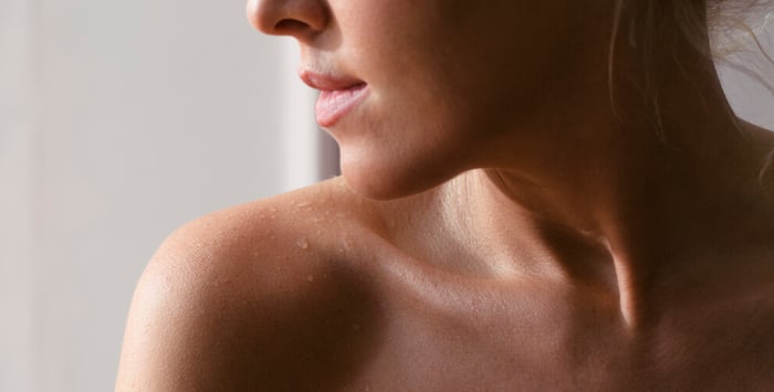 Close-up of dewy woman's shoulder and neck showing healthy hydrated skin with natural glow